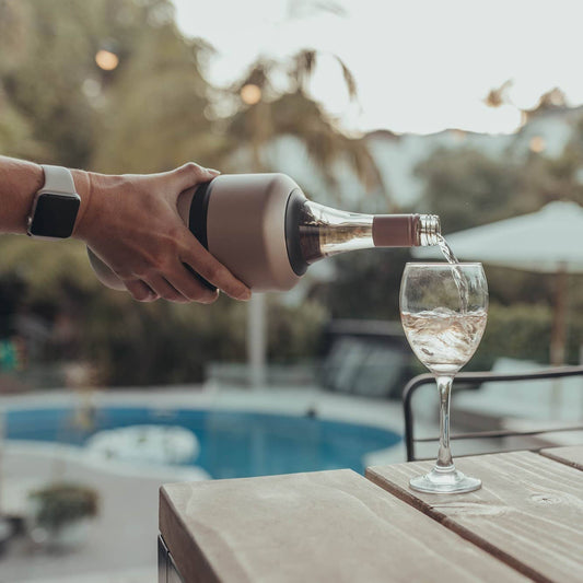 Person pouring wine into a glass by a poolside