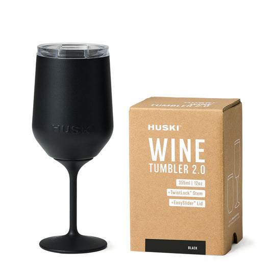 Black wine tumbler with Huski branding next to its packaging box on a white background