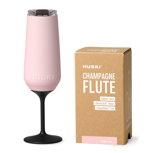 Pink champagne flute with black stem next to its packaging box on a white background