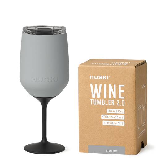 Gray wine tumbler with black stem next to its packaging on a white background