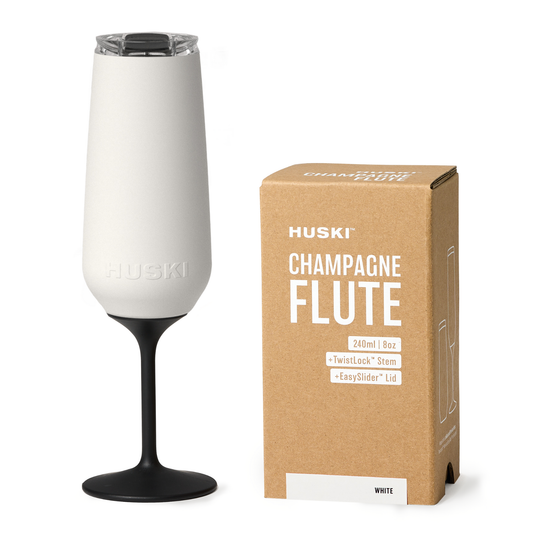 White champagne flute with black stem next to its packaging box on a white background
